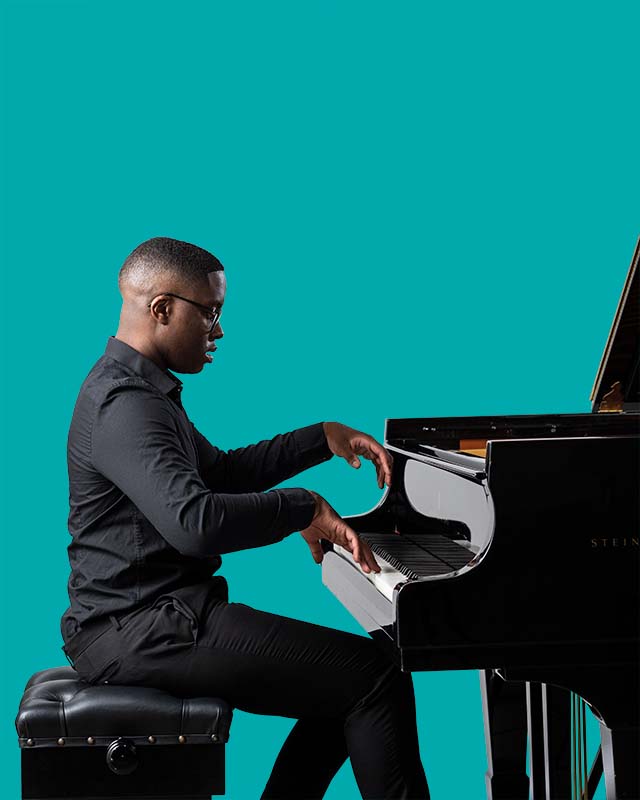 An RCM student playing a grand piano, against a turquoise background